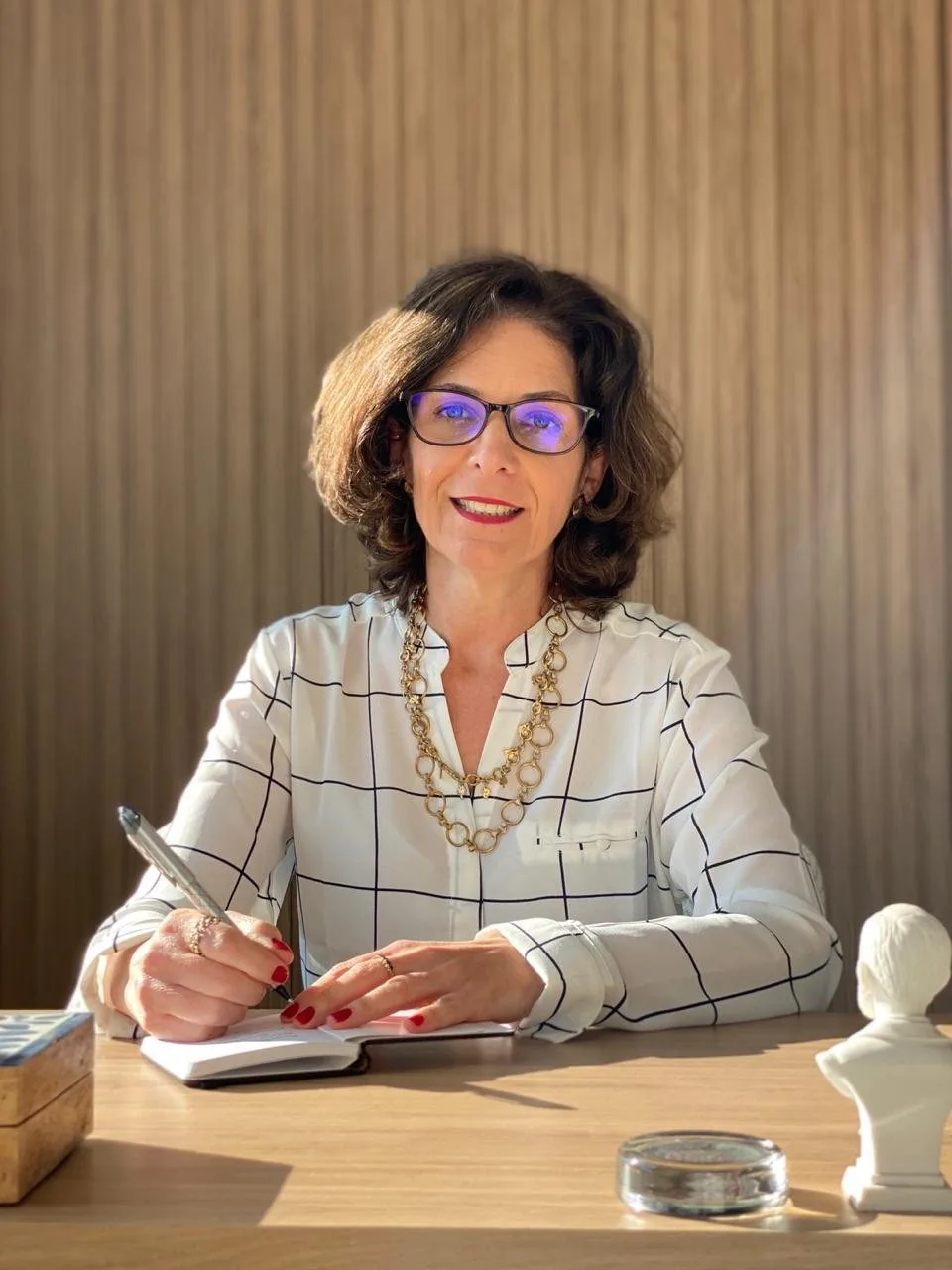 Gisela Mottin em seu consultório, escrevendo em um caderno